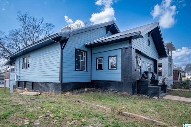 view of side of home featuring a yard, metal roof, and a chimney