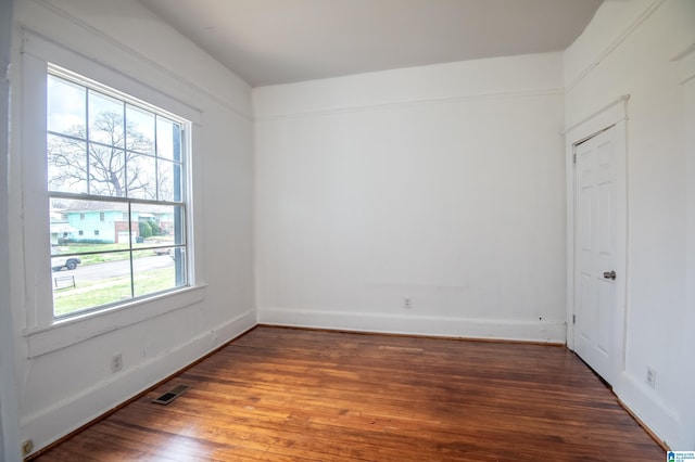 unfurnished room featuring wood finished floors, visible vents, and baseboards