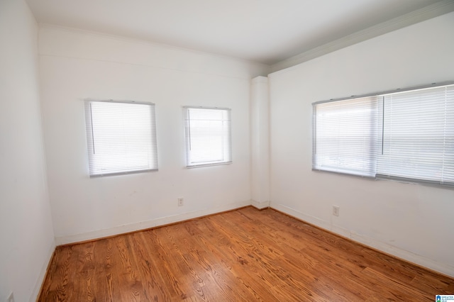 unfurnished room featuring baseboards, crown molding, and light wood finished floors