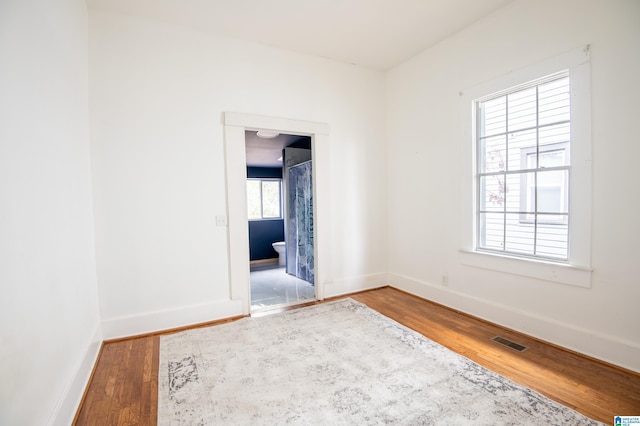 empty room featuring visible vents, baseboards, and wood finished floors