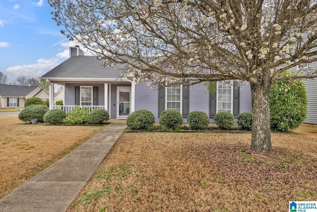 view of front of house with a porch, a chimney, and a front yard