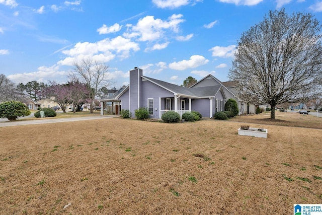 view of front facade with an attached carport, a front lawn, driveway, and a chimney