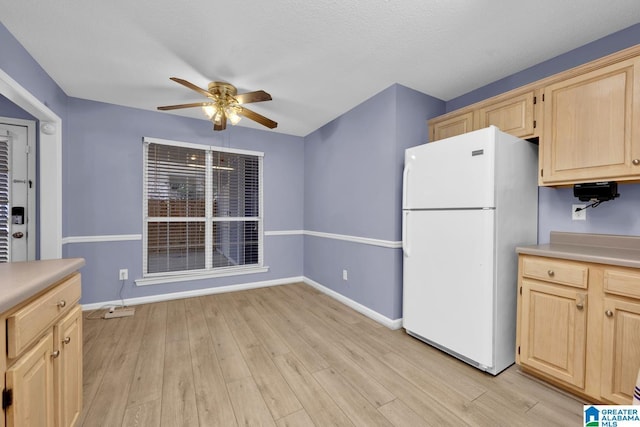 kitchen with light wood-style flooring, a ceiling fan, light brown cabinets, freestanding refrigerator, and light countertops