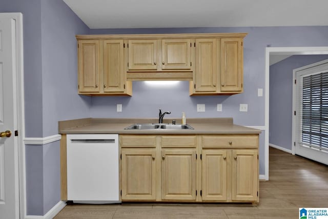 kitchen with light brown cabinets, dishwasher, light countertops, and a sink