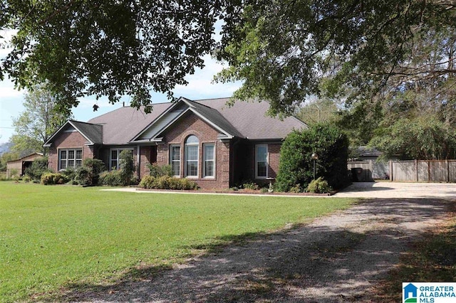 view of front of property with a front yard, fence, brick siding, and driveway