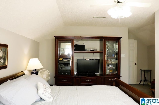 bedroom with visible vents, a textured ceiling, ceiling fan, and vaulted ceiling