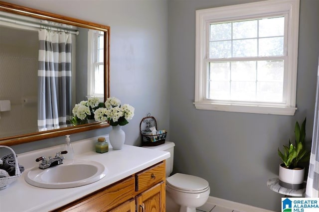 bathroom with vanity, a shower with curtain, toilet, and a healthy amount of sunlight