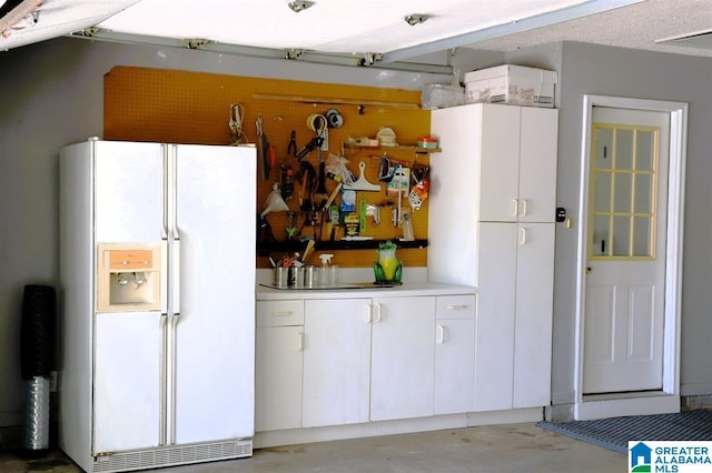 kitchen featuring light countertops, white cabinets, concrete floors, and white fridge with ice dispenser