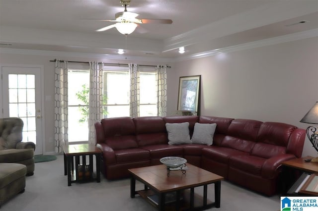 living room with a ceiling fan, crown molding, light colored carpet, and a raised ceiling