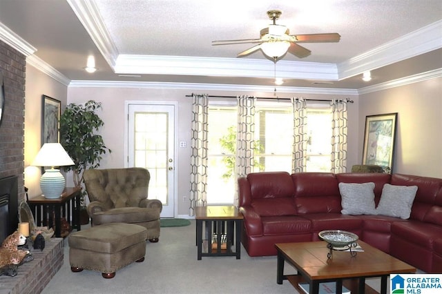 carpeted living area with a raised ceiling, a textured ceiling, a ceiling fan, and crown molding