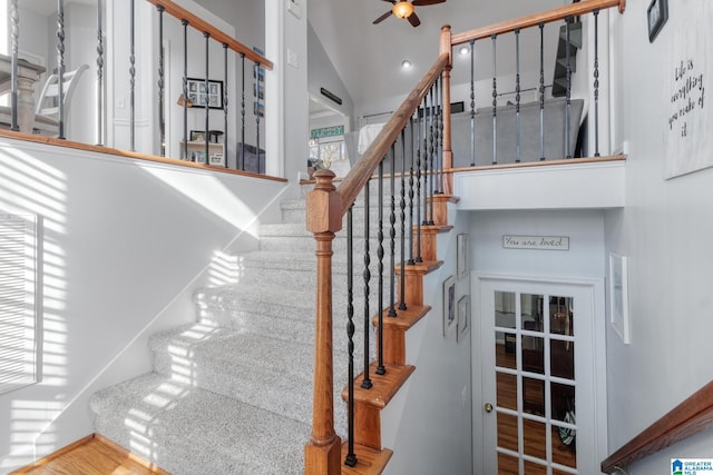 stairs with wood finished floors, baseboards, a ceiling fan, and vaulted ceiling