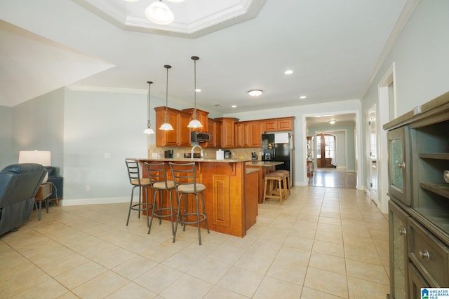 kitchen with stainless steel microwave, crown molding, a kitchen bar, brown cabinets, and a peninsula