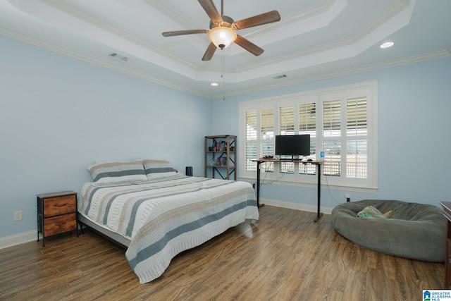 bedroom featuring a tray ceiling, wood finished floors, and ornamental molding