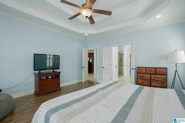 bedroom featuring a raised ceiling, wood finished floors, baseboards, and ornamental molding