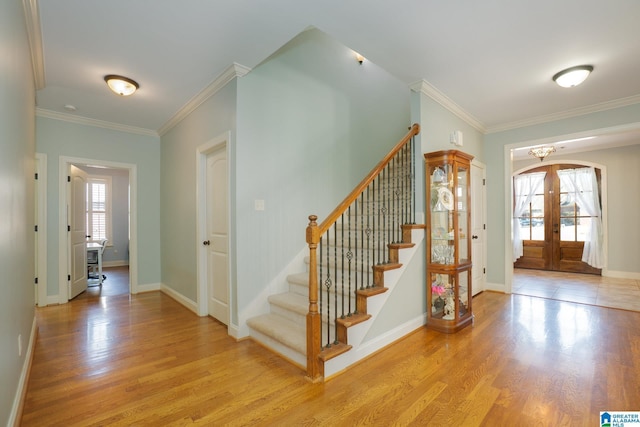 stairs featuring a healthy amount of sunlight, wood finished floors, crown molding, and an inviting chandelier