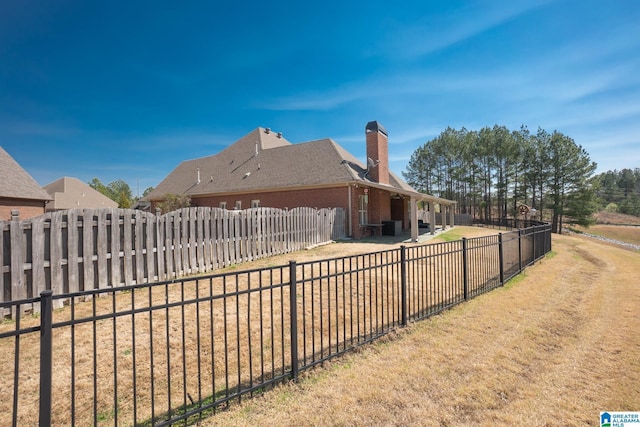 exterior space with a lawn, a patio, brick siding, fence private yard, and a chimney