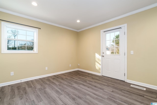 unfurnished room with visible vents, wood finished floors, recessed lighting, crown molding, and baseboards