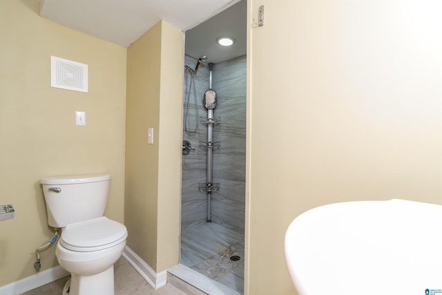 bathroom featuring a tile shower, tile patterned floors, toilet, and baseboards