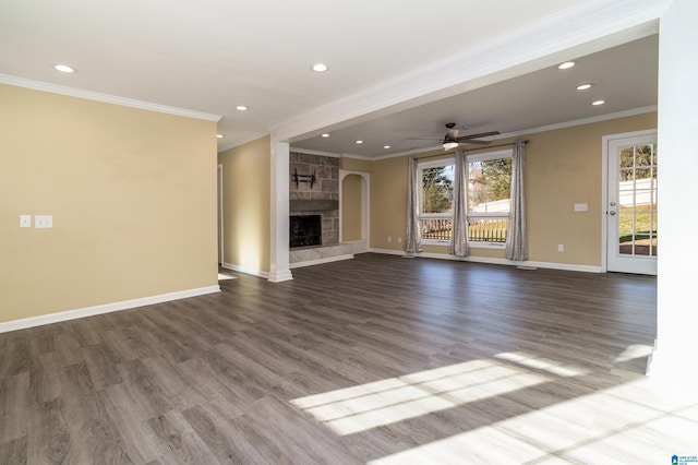 unfurnished living room with baseboards, ornamental molding, a stone fireplace, wood finished floors, and a ceiling fan