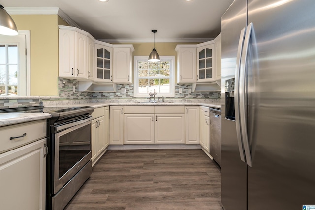 kitchen with crown molding, hanging light fixtures, white cabinets, stainless steel appliances, and a sink