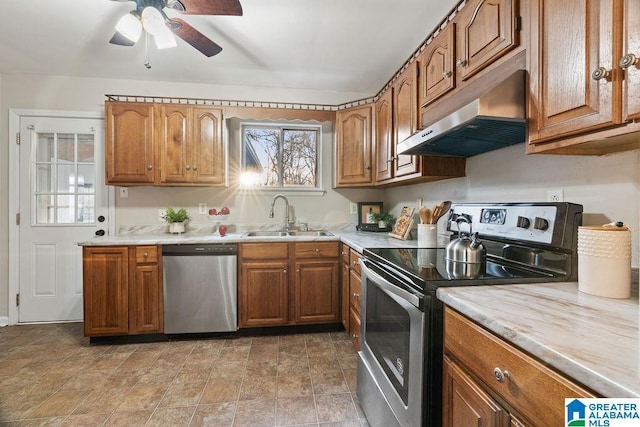 kitchen featuring a sink, stainless steel appliances, light countertops, under cabinet range hood, and brown cabinets