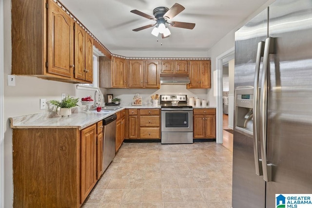 kitchen with a sink, range hood, brown cabinets, and stainless steel appliances