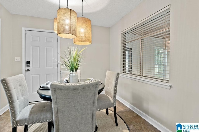 dining room featuring tile patterned floors, baseboards, and a textured ceiling