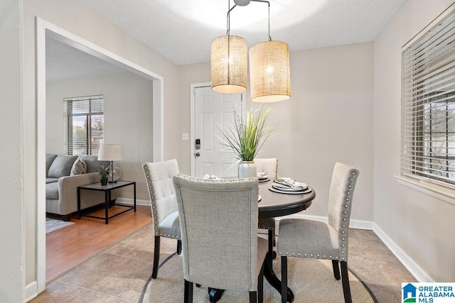 dining space featuring tile patterned floors, baseboards, and a textured ceiling