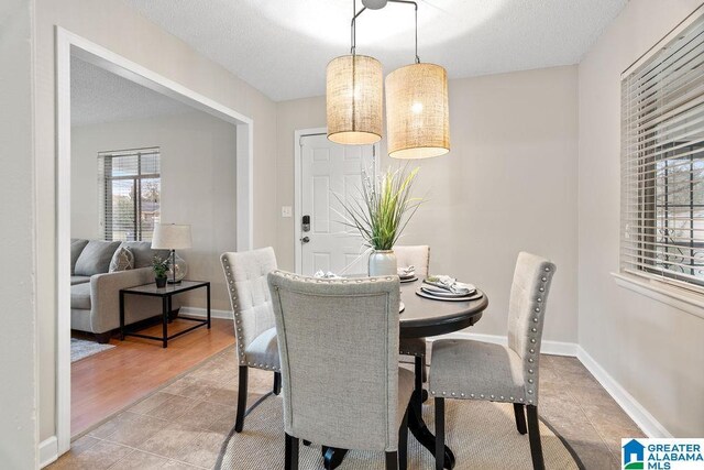 tiled dining space featuring baseboards and a textured ceiling