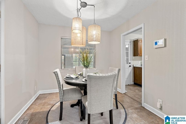 dining area featuring visible vents, baseboards, and a textured ceiling