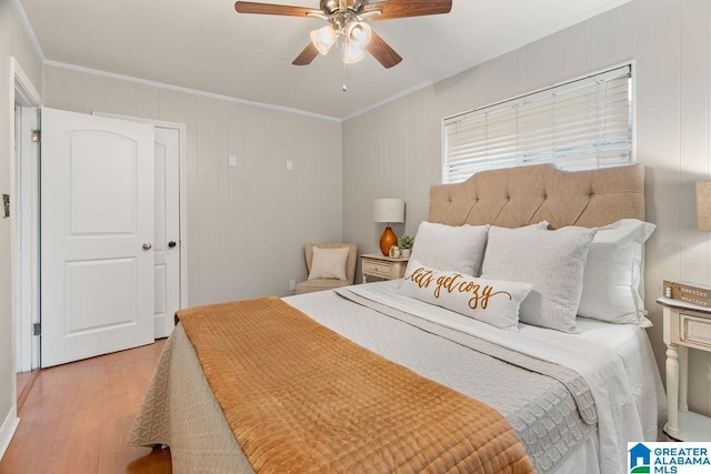 bedroom featuring light wood-type flooring, ornamental molding, and a ceiling fan