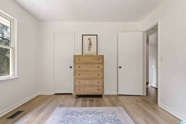 unfurnished bedroom featuring visible vents, baseboards, and wood finished floors