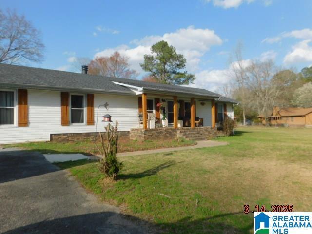 ranch-style home featuring covered porch and a front lawn