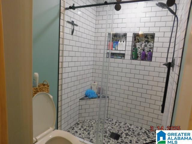 bathroom featuring a shower stall and toilet