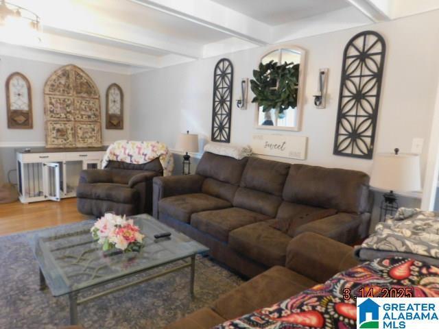 living area with beamed ceiling and wood finished floors