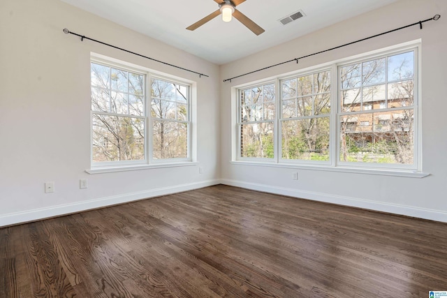 spare room with dark wood finished floors, baseboards, visible vents, and ceiling fan