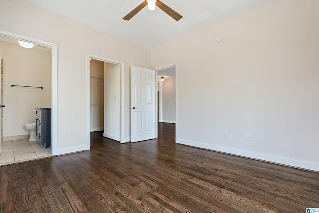 unfurnished bedroom featuring a spacious closet, wood finished floors, baseboards, and a closet