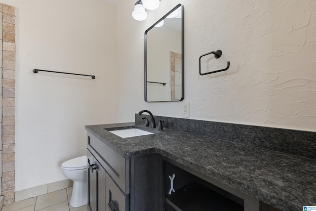 bathroom with tile patterned flooring, toilet, vanity, and a textured wall