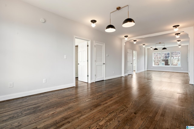 unfurnished living room featuring baseboards and dark wood-style flooring