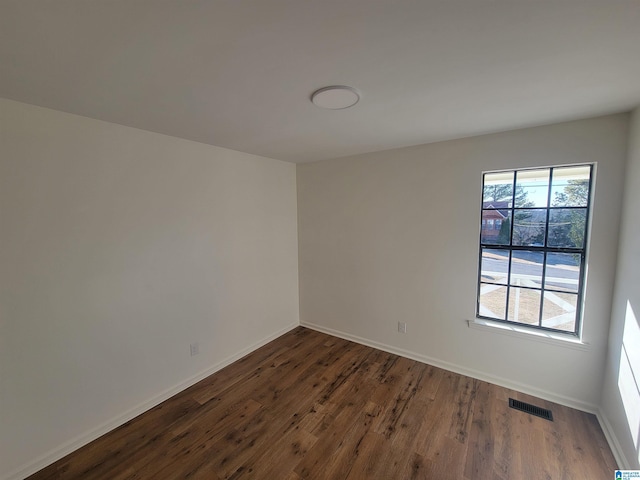 unfurnished room with visible vents, baseboards, and dark wood-type flooring