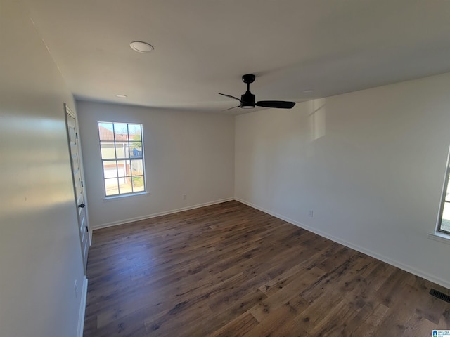 empty room featuring dark wood finished floors, visible vents, baseboards, and a ceiling fan