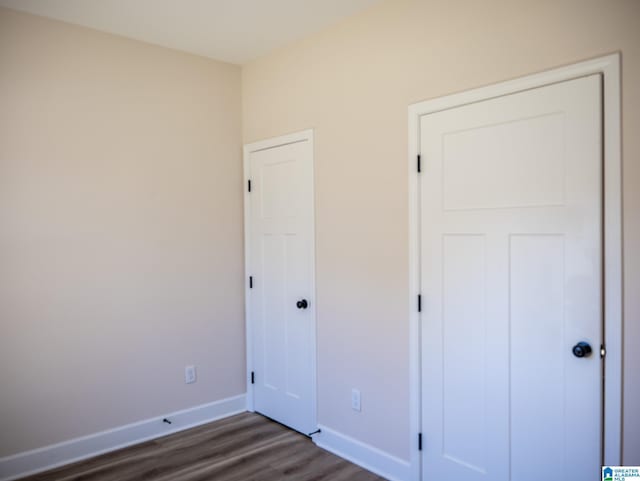 unfurnished bedroom featuring a closet, baseboards, and dark wood-style flooring