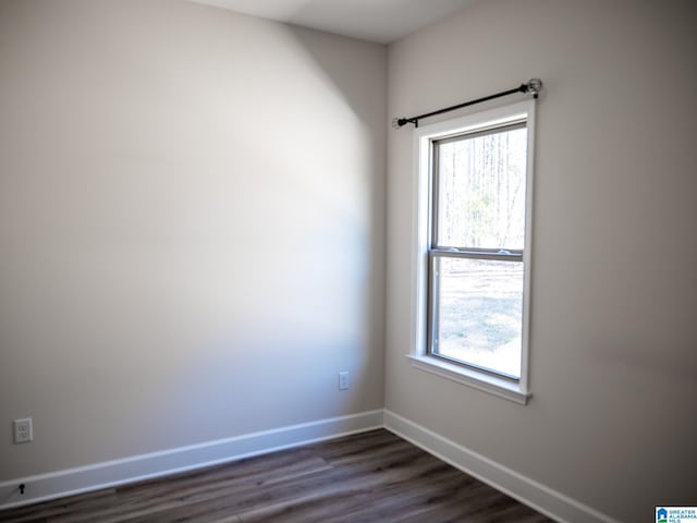 empty room with dark wood-type flooring and baseboards