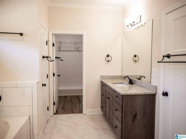 full bathroom with vanity, a bathing tub, a walk in closet, crown molding, and marble finish floor