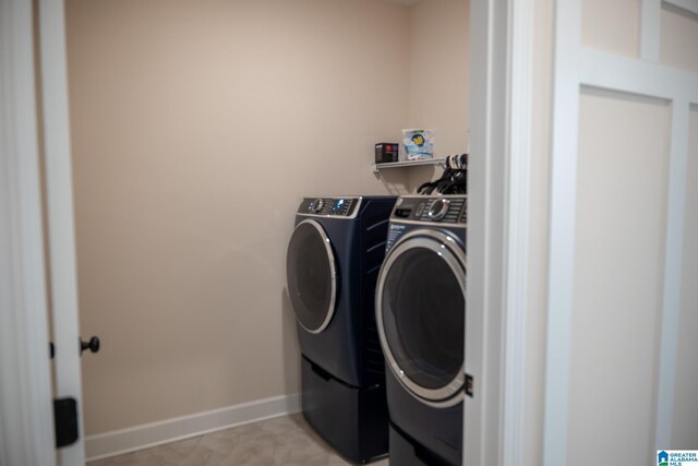 washroom featuring washing machine and clothes dryer, laundry area, and baseboards