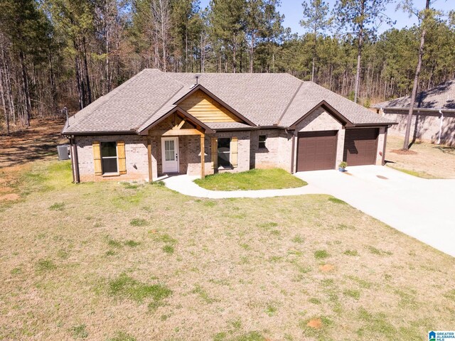 view of front of property with driveway, a front lawn, a garage, a view of trees, and brick siding