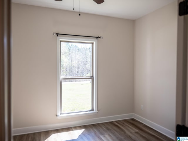 empty room featuring wood finished floors, a ceiling fan, and baseboards