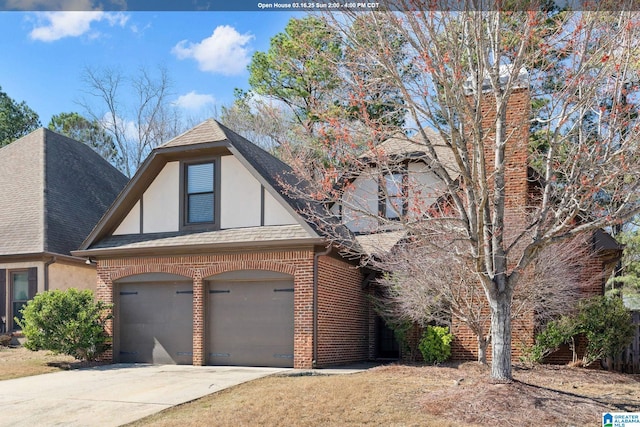 tudor house featuring brick siding, a shingled roof, stucco siding, a garage, and driveway