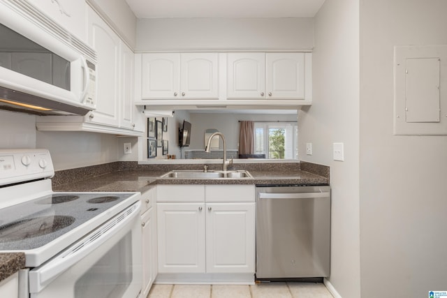 kitchen featuring electric panel, white appliances, dark countertops, and a sink