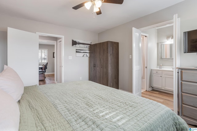 bedroom featuring a ceiling fan, light wood-style floors, baseboards, and connected bathroom